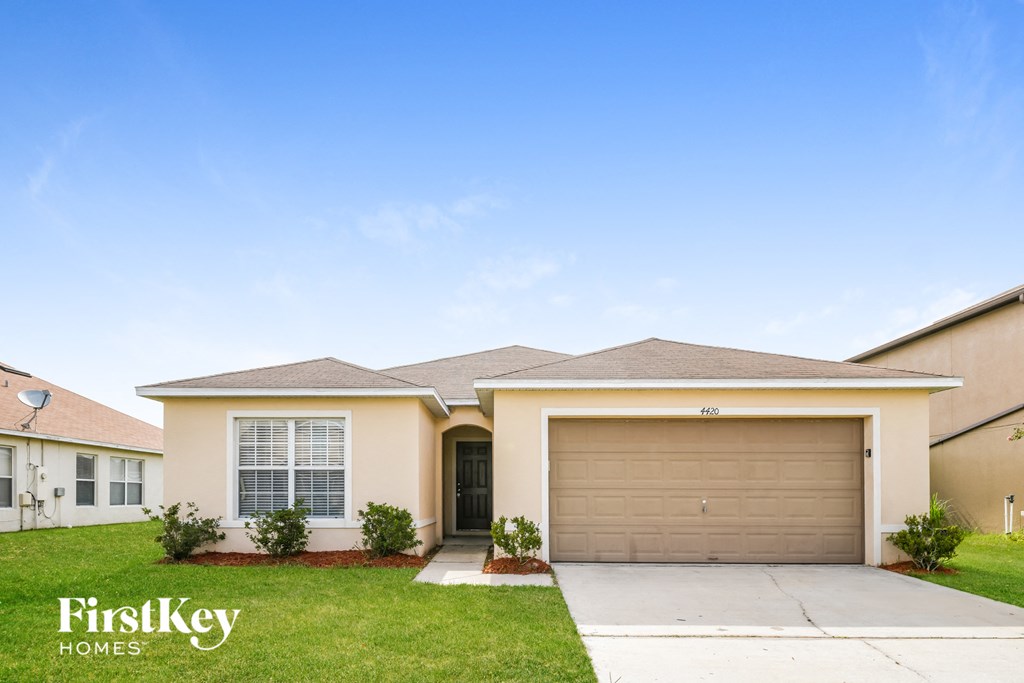 a beige house with a garage door and a lawn