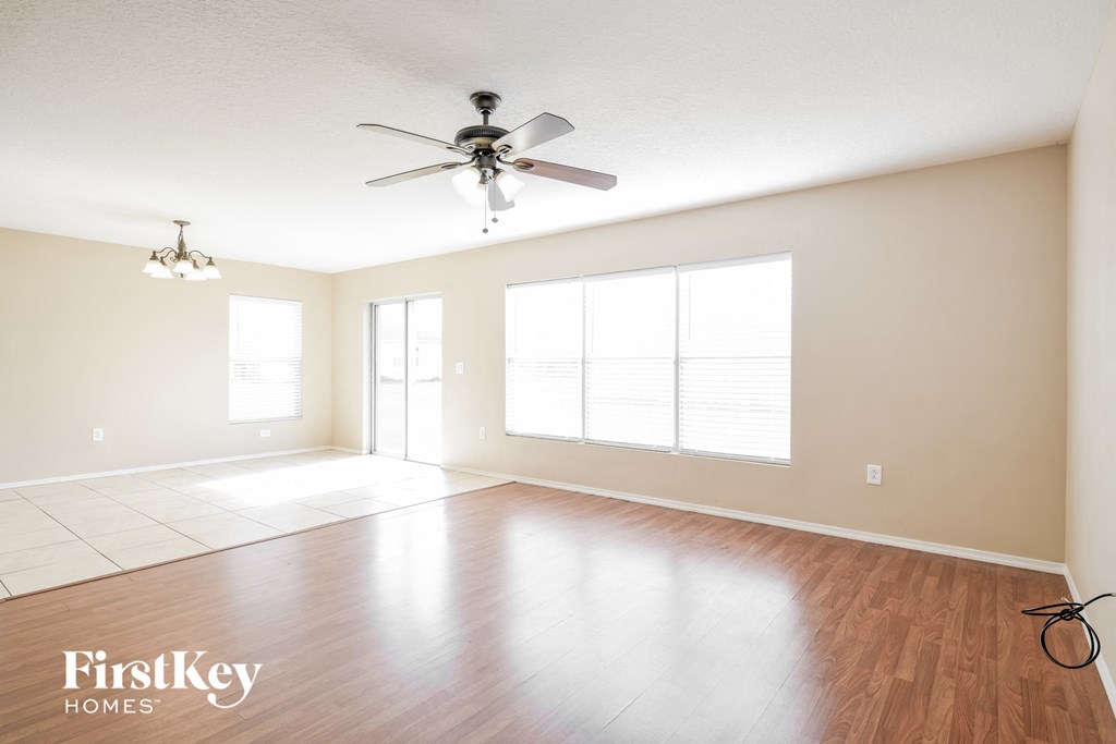 an empty living room with a ceiling fan and a large window