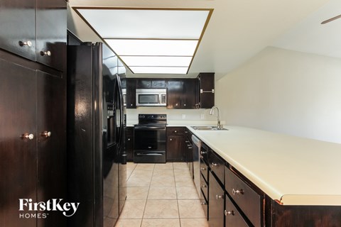 A kitchen with a refrigerator, microwave, oven, and sink.