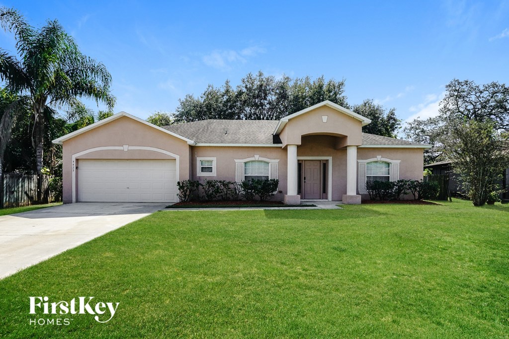 A house with a well-manicured lawn and a clear blue sky above.