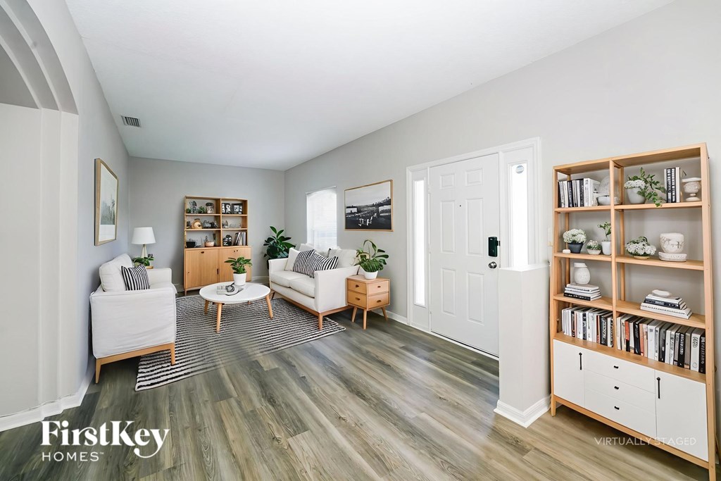 A virtual staging of a home interior with a living room, dining area, and a bookshelf.