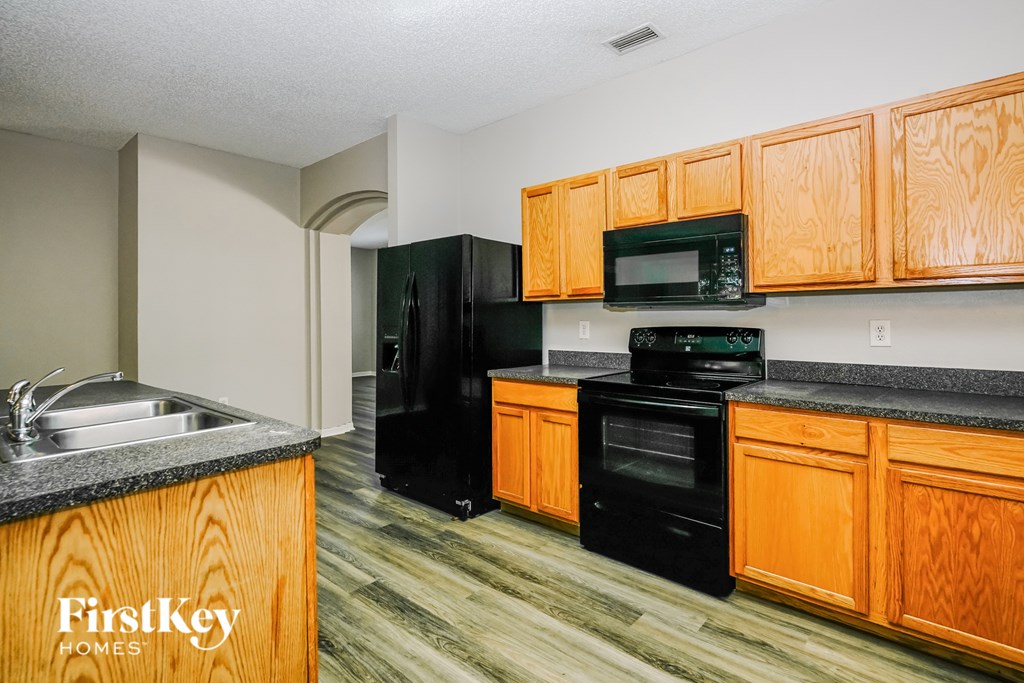 A kitchen with wooden cabinets and black appliances.