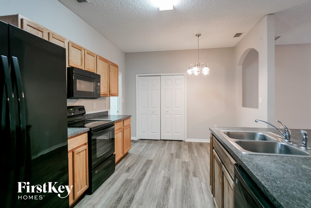 A kitchen with a black fridge, wooden cabinets, and a white door.