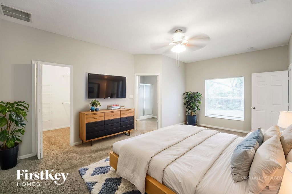 A bedroom with a bed, dresser, and ceiling fan.