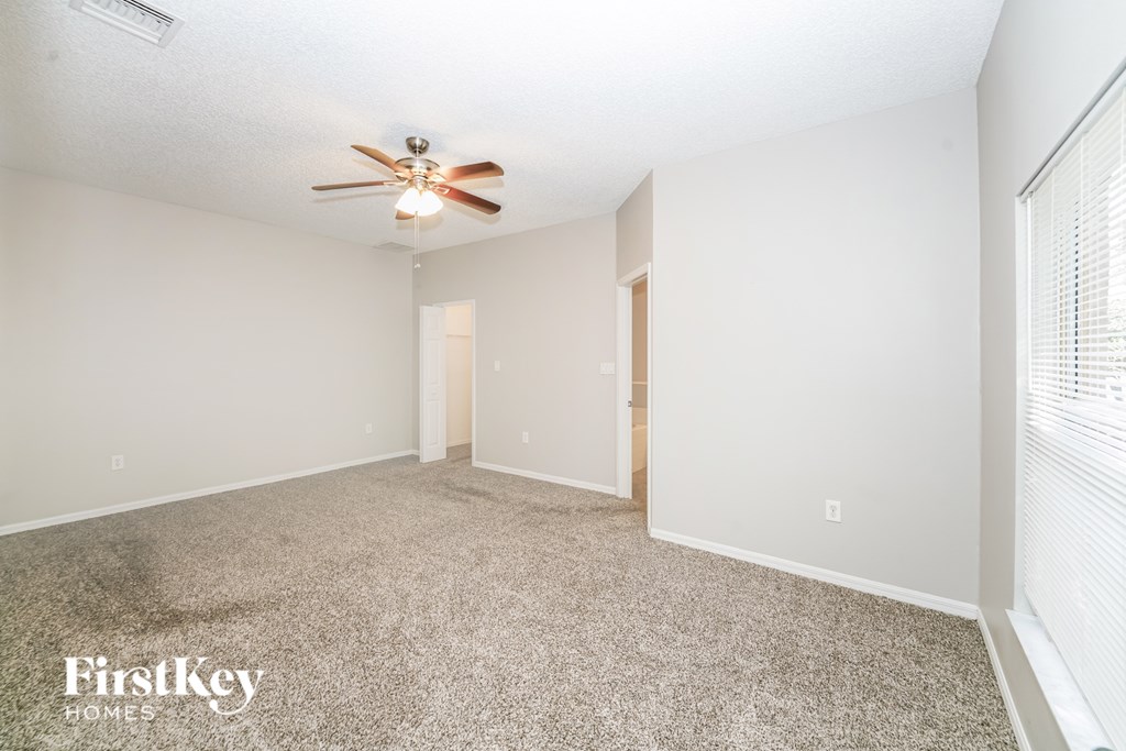 A spacious room with a ceiling fan and carpeted floor.