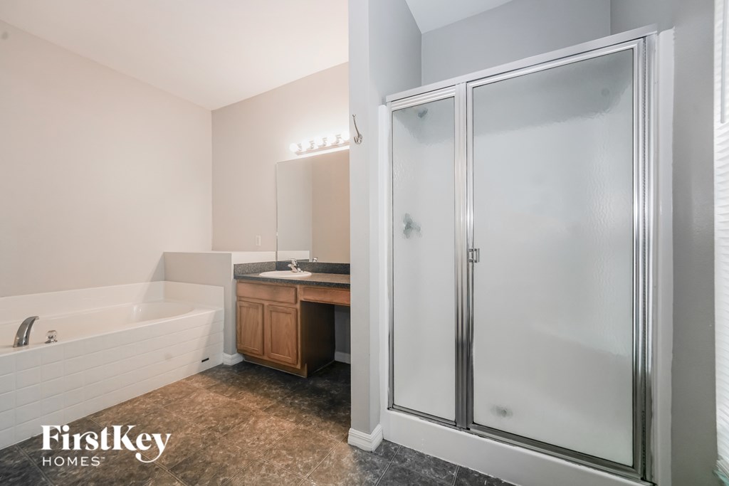 A bathroom with a tub, sink, and shower door.
