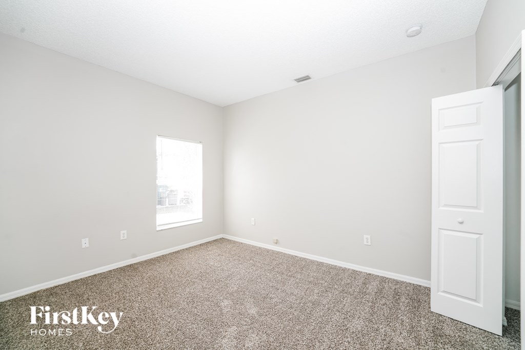 A room with a carpet floor and a door on the right side.
