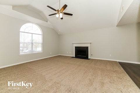 an empty living room with a fireplace and a ceiling fan
