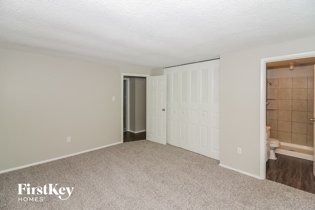 a bedroom with a closet and a bathroom with a toilet