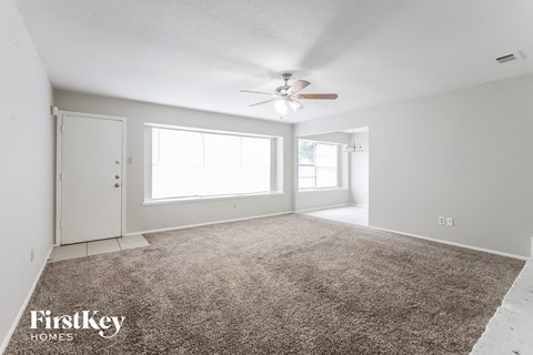 A spacious room with a carpeted floor and a ceiling fan.