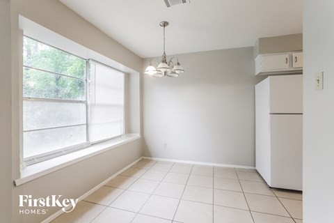 A white kitchen with a refrigerator and a window.