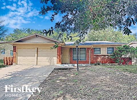 a brick house with two garage doors and a tree