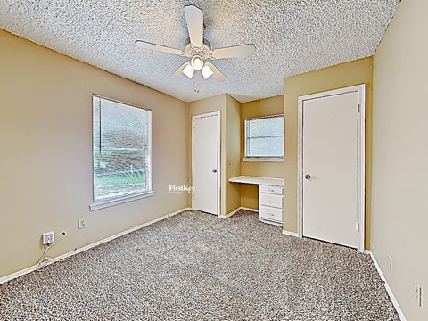 an empty bedroom with a ceiling fan and a desk
