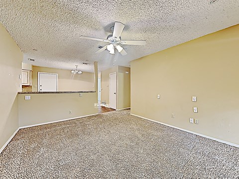 an empty living room with a ceiling fan