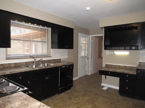 A kitchen with black cabinets and a granite countertop.
