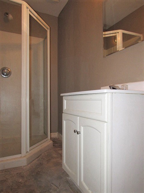 A white bathroom cabinet with a glass door.