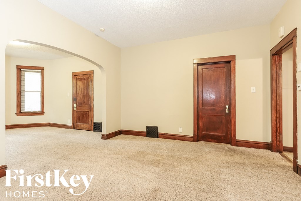 a empty living room with two doors and a carpeted floor