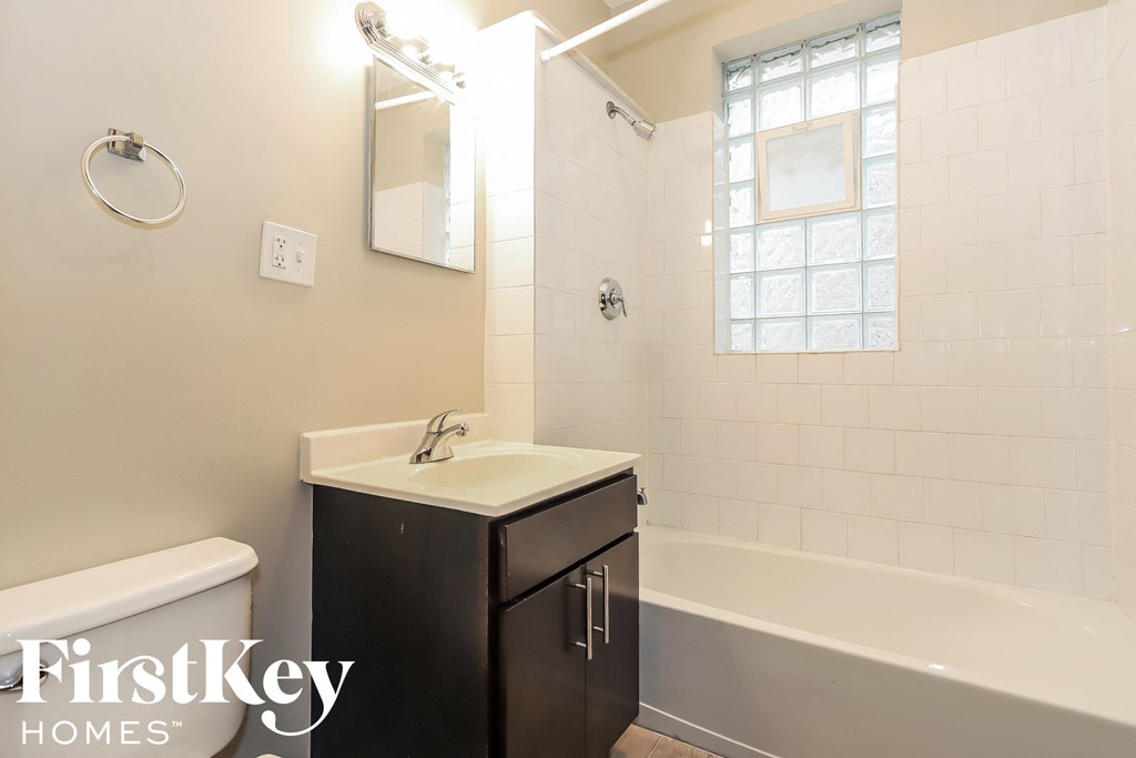 a white bathroom with a sink and a tub and a window