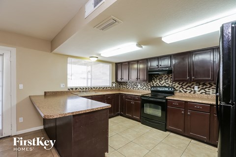 A kitchen with brown cabinets and a black refrigerator.