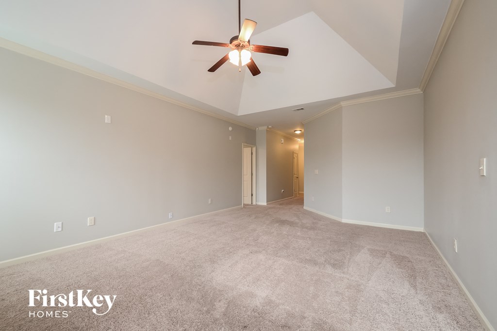 a spacious living room with carpet and a ceiling fan