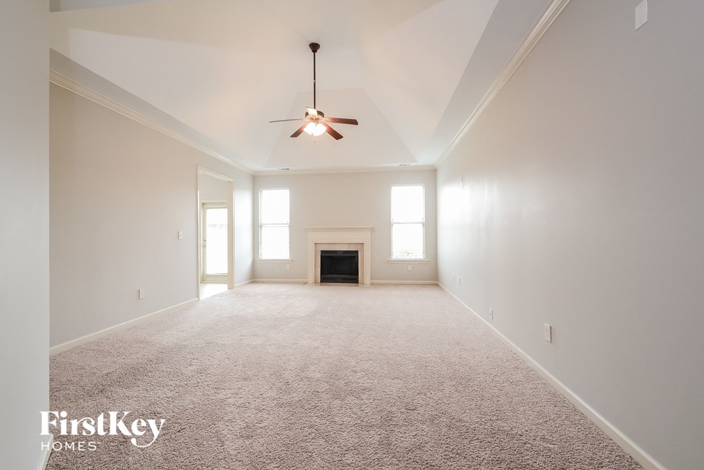an empty living room with a ceiling fan and a fireplace