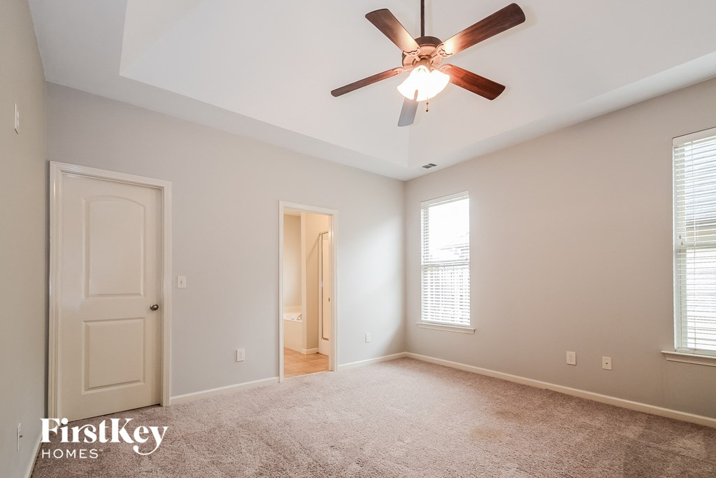 a living room with a ceiling fan and a door to a hallway
