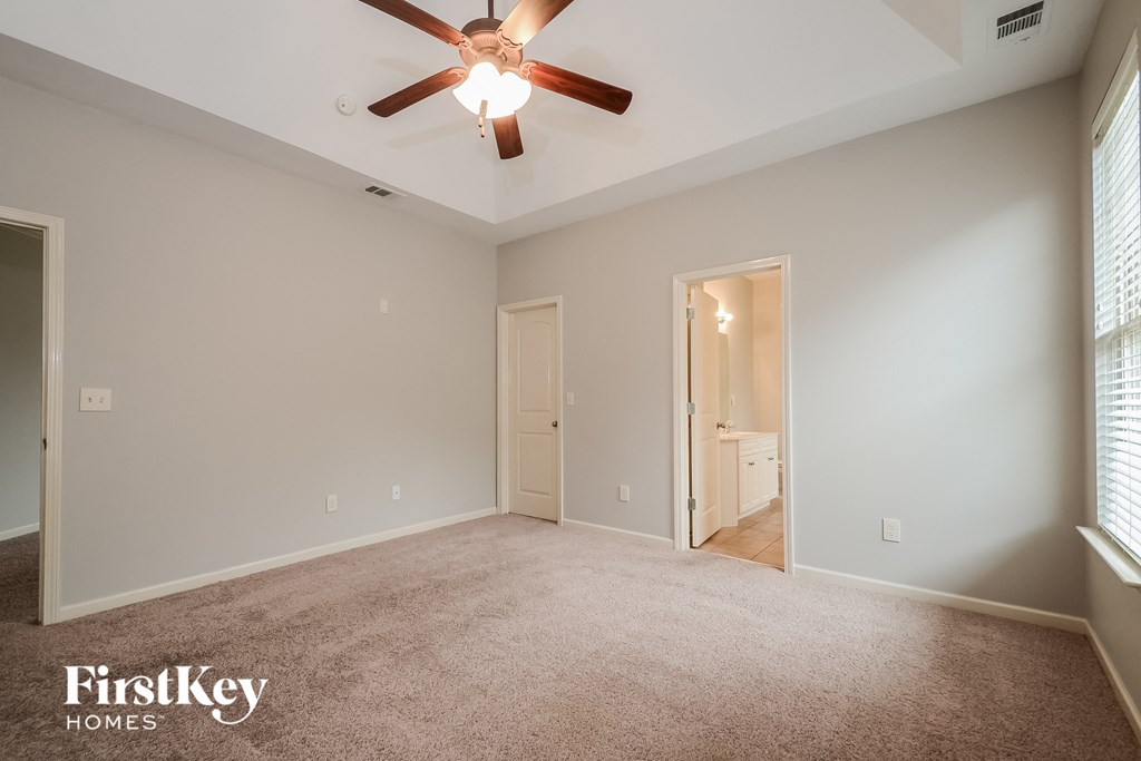 an empty living room with a ceiling fan and a carpet