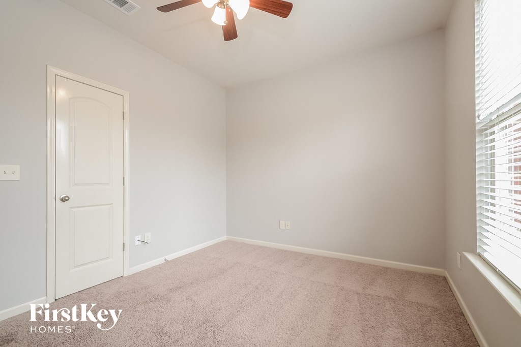 an empty room with a ceiling fan and a window
