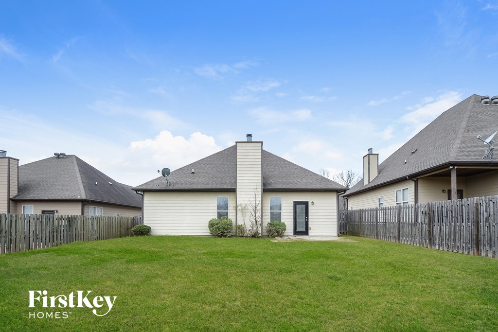 the backyard of a house with a green lawn and a wooden fence