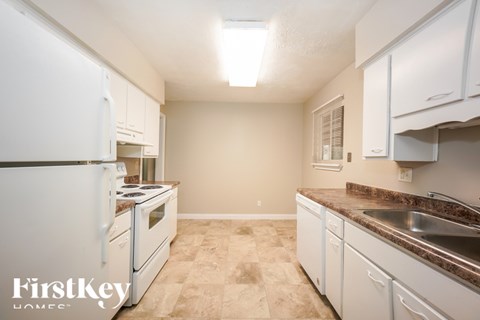 A kitchen with a white refrigerator and cabinets.