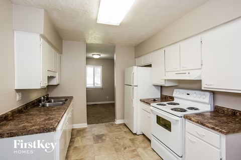 A kitchen with white appliances and cabinets.