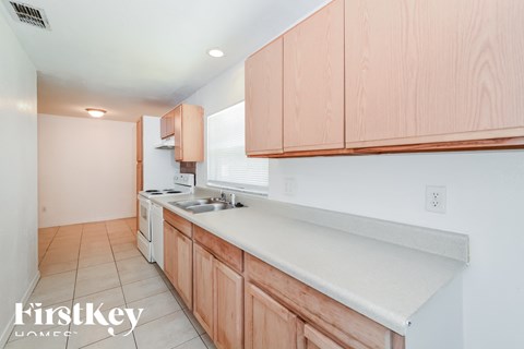 a kitchen with white countertops and wooden cabinets and a sink and stove