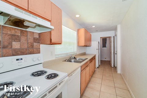 a kitchen with white appliances and wooden cabinets and a white stove top oven