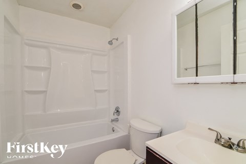 a white bathroom with a tub and a sink and a toilet