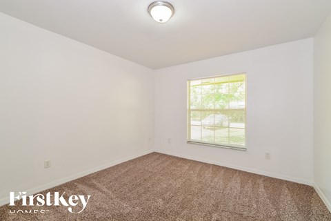 the living room of a small white house with carpet and a window