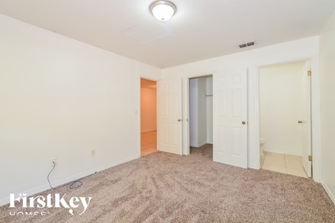 a bedroom with a carpeted floor and a door to a closet