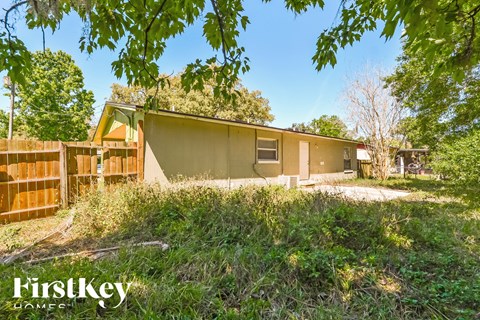 the front of a house with a yard and a fence