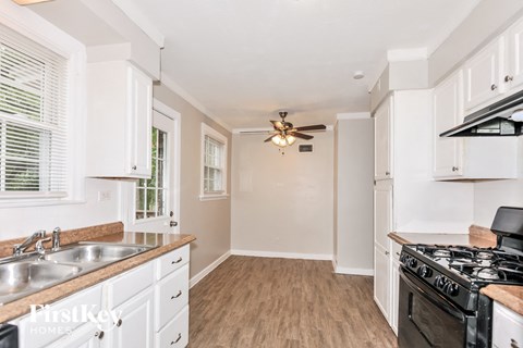 a kitchen with white cabinets and a stove and a ceiling fan