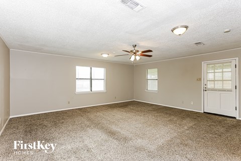 a living room with carpet and a ceiling fan