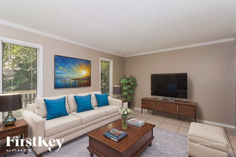 A living room with a couch, a coffee table, a television, and a painting on the wall.