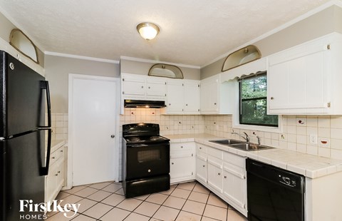 A kitchen with black appliances and white cabinets.