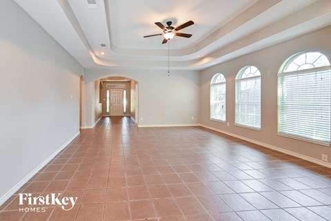 A spacious room with a ceiling fan and tiled flooring.