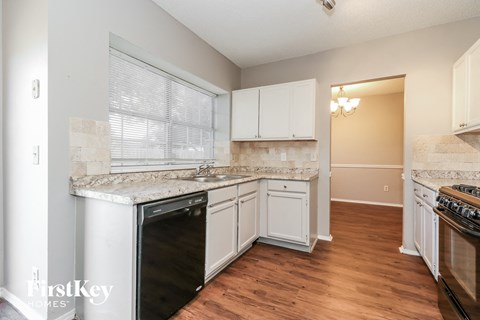 A kitchen with a black dishwasher and white cabinets.