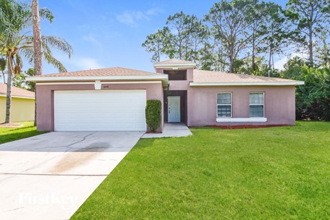a pink house with a driveway and a garage door