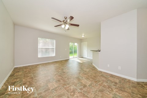 the spacious living room with tile flooring and a ceiling fan