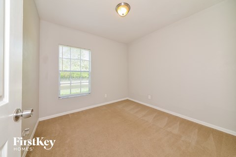 a bedroom with white walls and carpet and a window