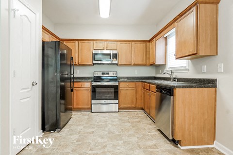 A kitchen with wooden cabinets and a black refrigerator.
