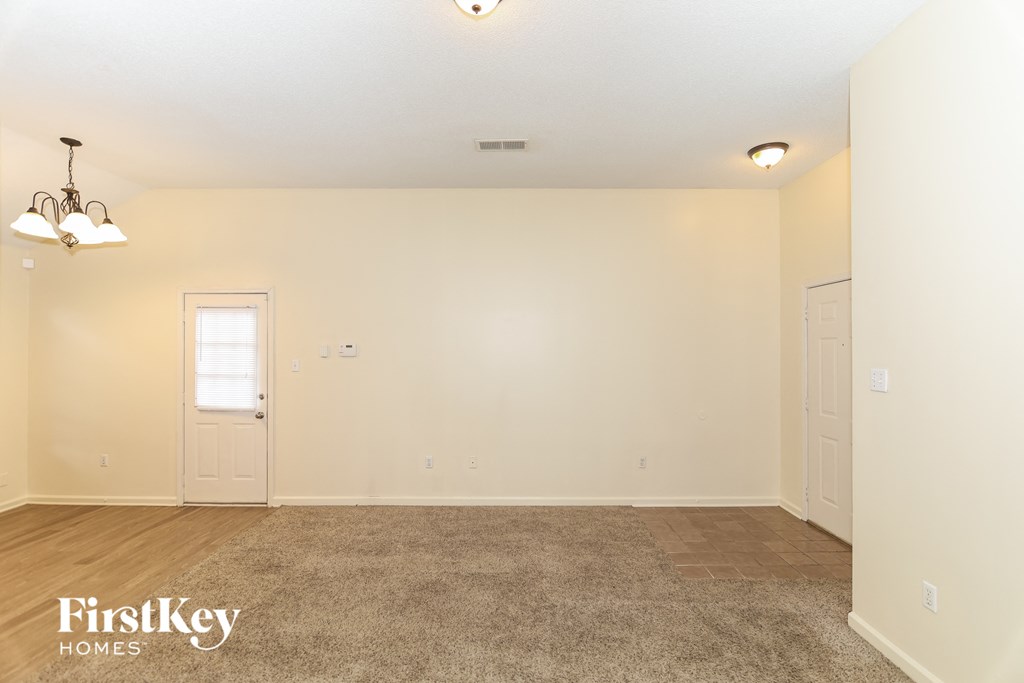 A spacious room with a door and a carpet on the floor.