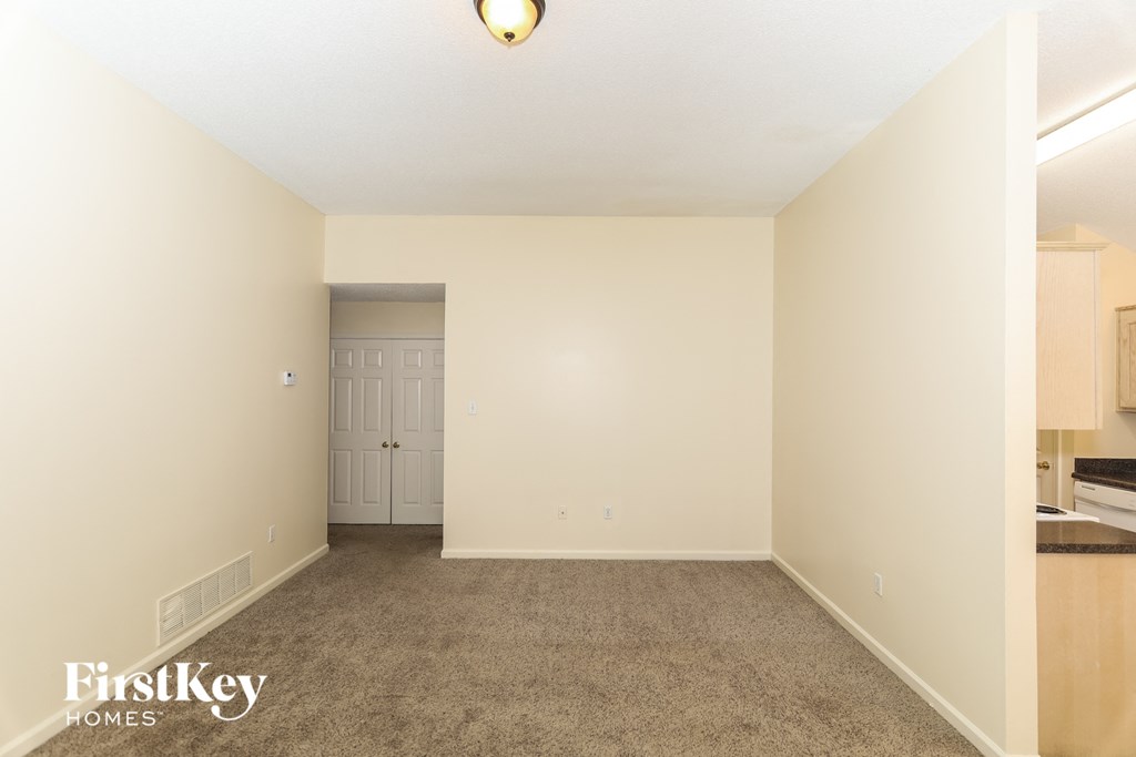 A room with a carpeted floor and a door in the background.