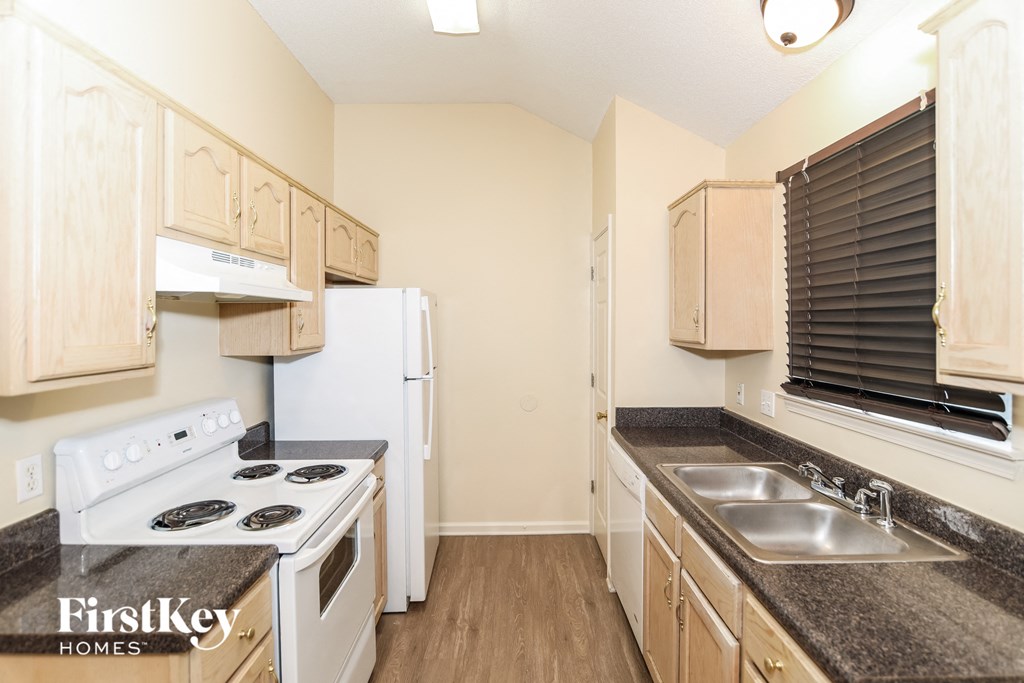 A kitchen with a stove top oven, refrigerator, and sink.